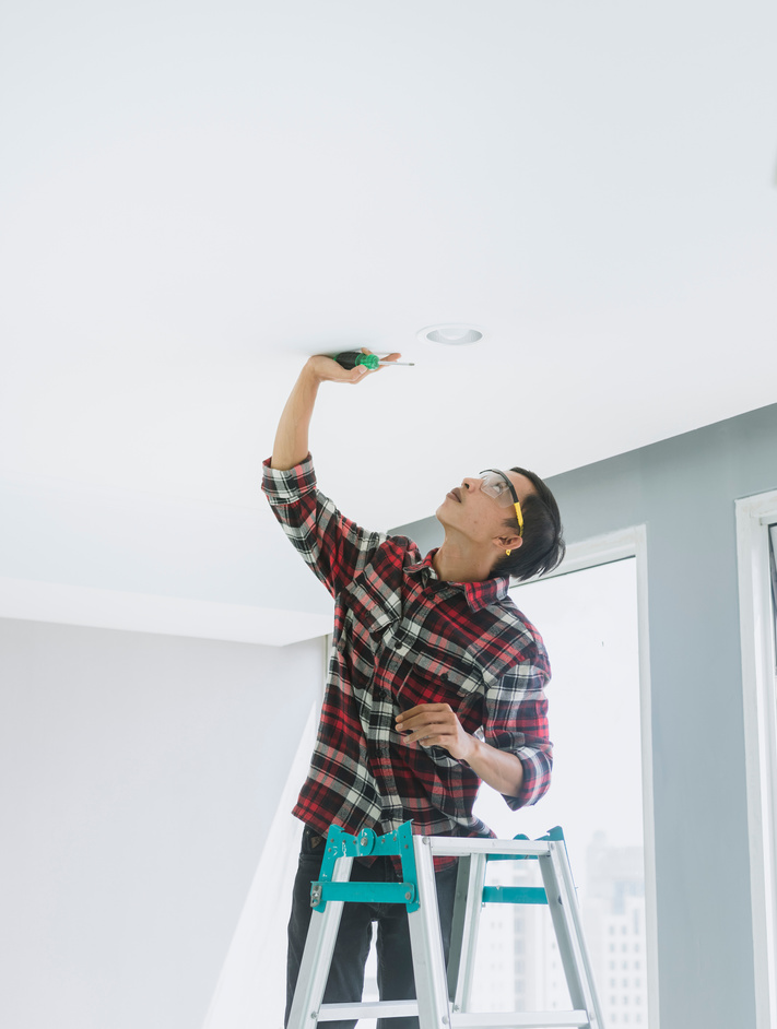 Repairman Installing a Light Bulb on the Ceiling
